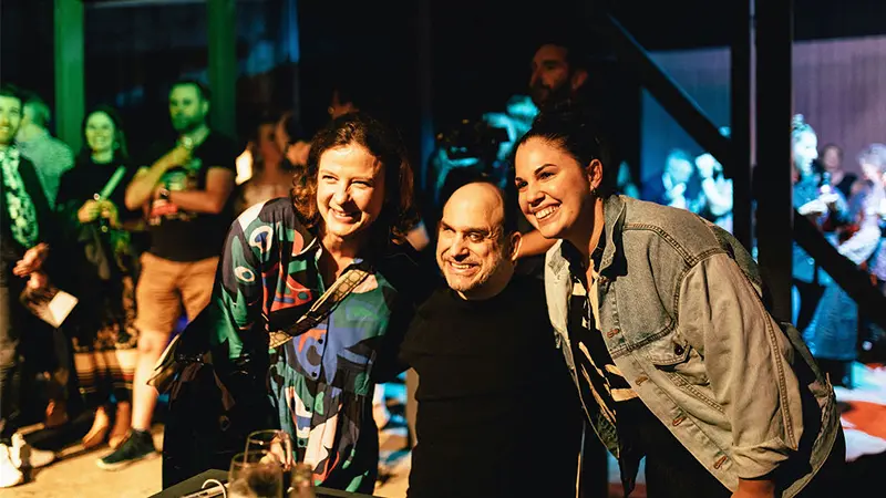Two female concert goers posing for a photo with performer Brenden Borellini